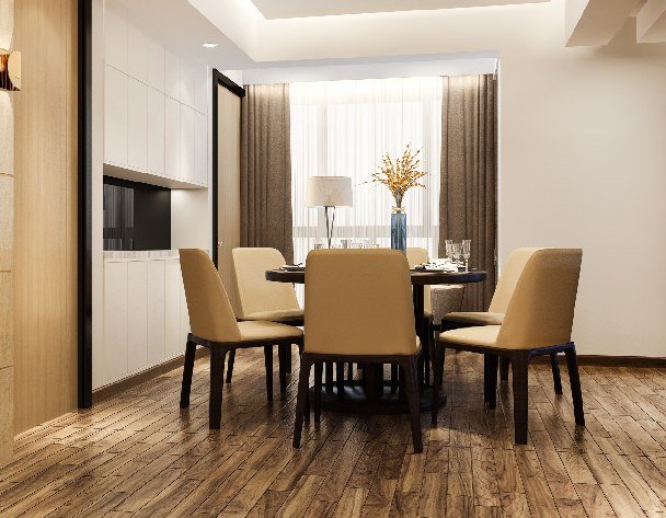 wooden parquet flooring installed, accompanied by a table and chair in a small room.